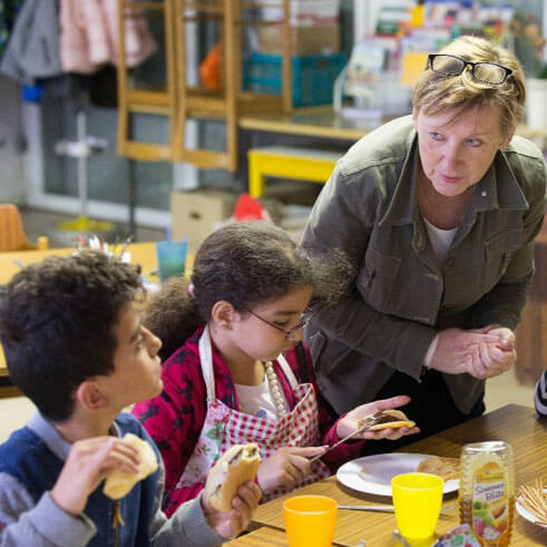 An adult volunteer assists children with their lunch. Photo courtesy Connectional Table.