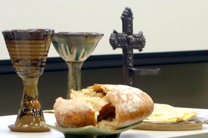Communion table with chalices, broken bread, and a cross. Image courtesy Connectional Table.