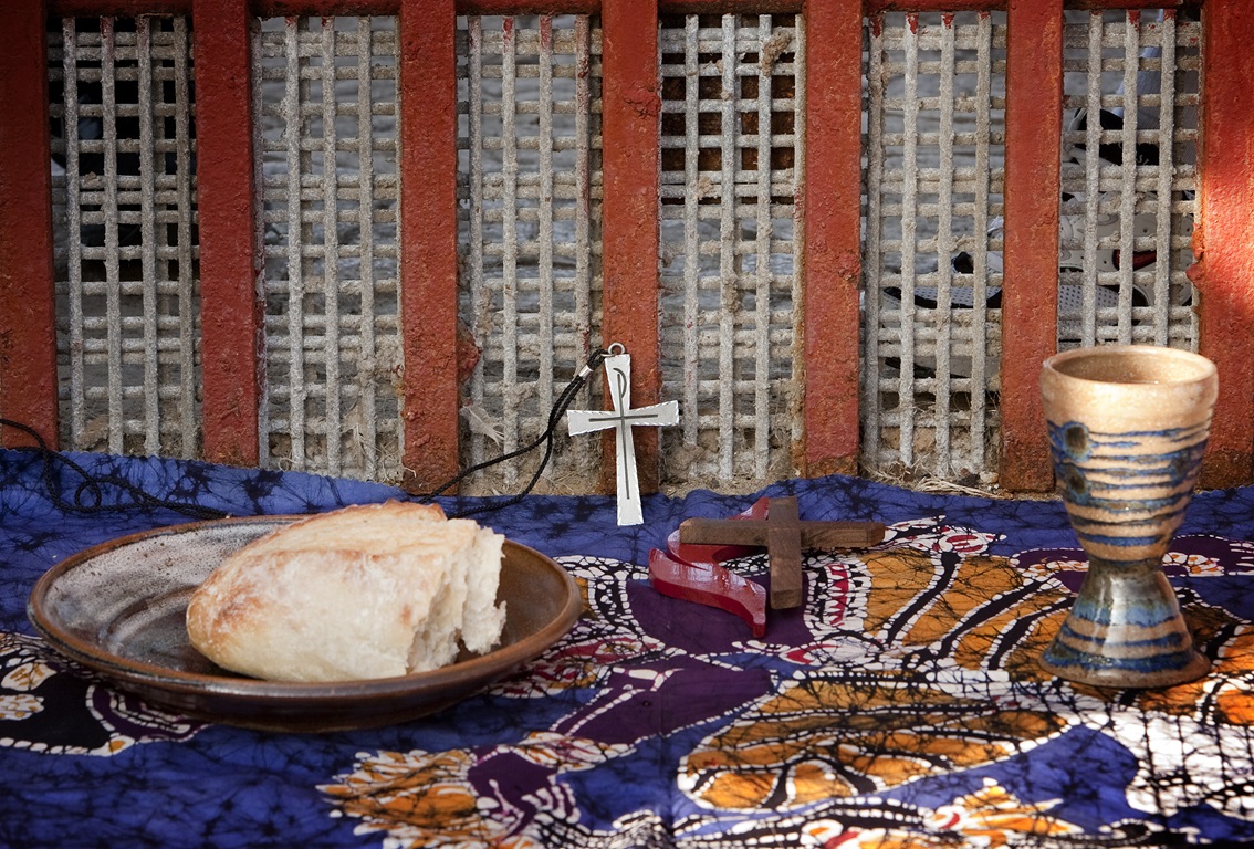 The elements of Holy Communion are laid out against the Mexico side of the border fence between Tijuana and San Diego during a cross-border service at El Faro park in Tijuana, Mexico. Photo by Mike DuBose, United Methodist Communications. 