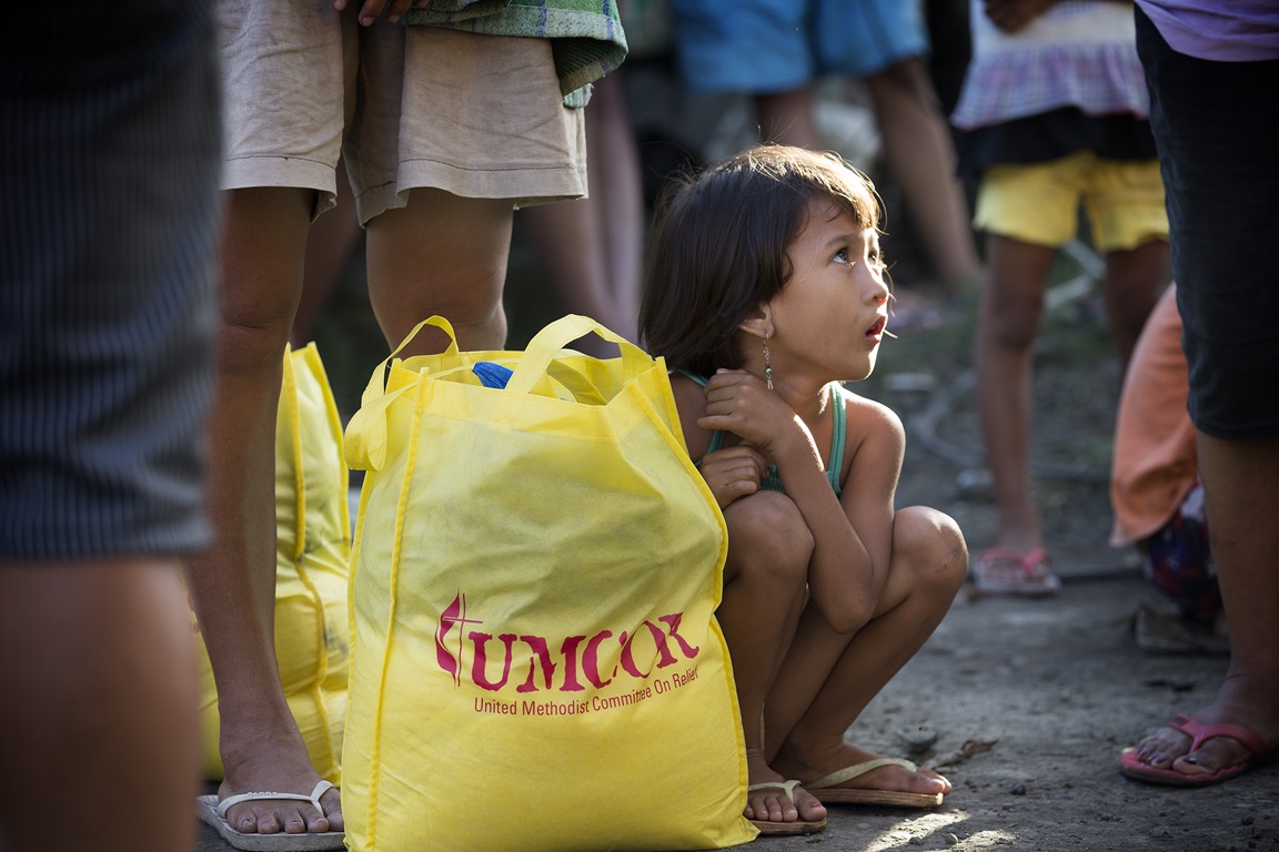Donna-Grace Orbong, 5, sits with her family's food bag following a distribution by the United Methodist Committee on Relief for survivors of Typhoon Haiyan in Tacloban, Philippines. Photo by Mike DuBose, UMNS