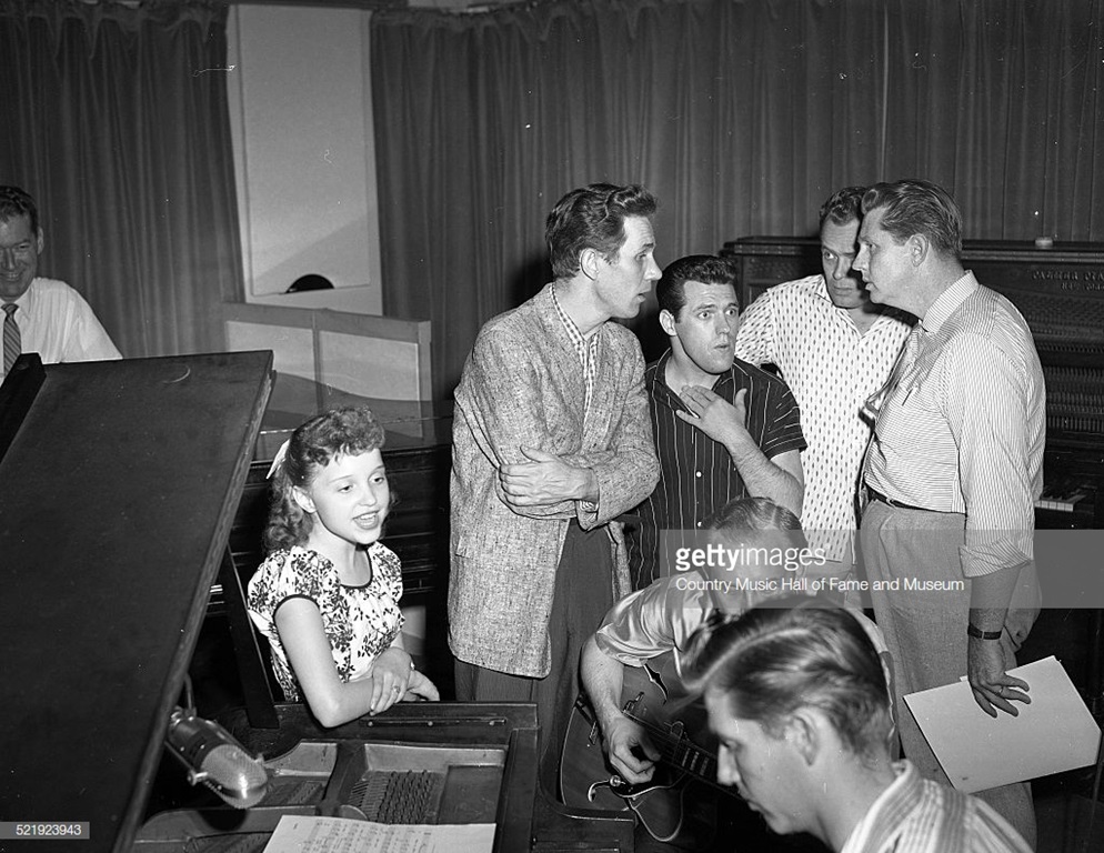 RCA artist Libby Horne recording session at Television, Radio, and Film Commission of the Methodist Church, (TRAFCO), Nashville, 1955 - 1957. RCA then rented this studio and office space from the Methodist Church. L-R: KWTO announcer Joe Slattery, Horne, Chet Atkins, Foggy River Boys member Charlie Hodge (hand on chest), guitarist Homer Haynes, pianist Floyd Cramer in foreground, Foggy River Boys members Earl Taylor and Monty Matthews. Photo by Elmer Williams/Country Music Hall of Fame and Museum/Getty Images.