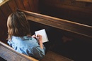Woman sitting in a church pew writing. Image by Tom Keenan, Lightstock.com.