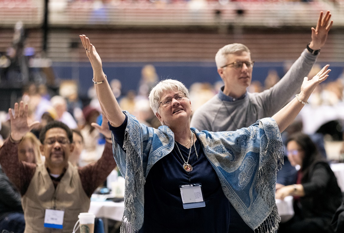Tennessee Conference delegate Holly Neal (front) raises her arms in praise  during a day of prayer at the 2019 United Methodist General Conference in St. Louis. She is joined by Tennessee delegates the Revs. Stephen Handy (left) and Jacob Armstrong (standing). Photo by Mike DuBose, UMNS. 