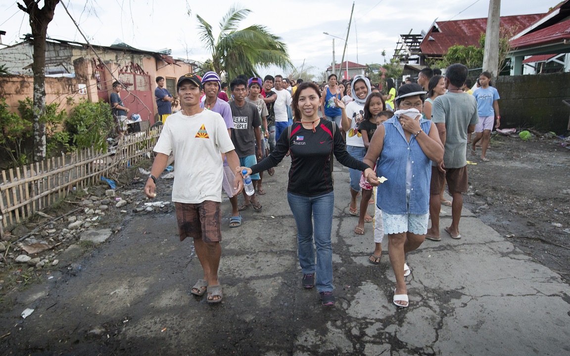 Ciony Ayo-Eduarte (center) leads survivors of Typhoon Haiyan to a food distribution by the United Methodist Committee on Relief in Tacloban, Philippines. Ayo-Eduarte is manager for UMCOR in the Philippines. Photo by Mike DuBose, UMNS