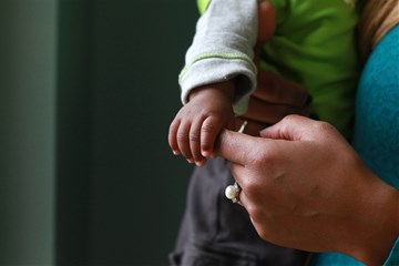 A baby holds fast to his mother's hand. Photo by Kathleen Barry, United Methodist Communications.