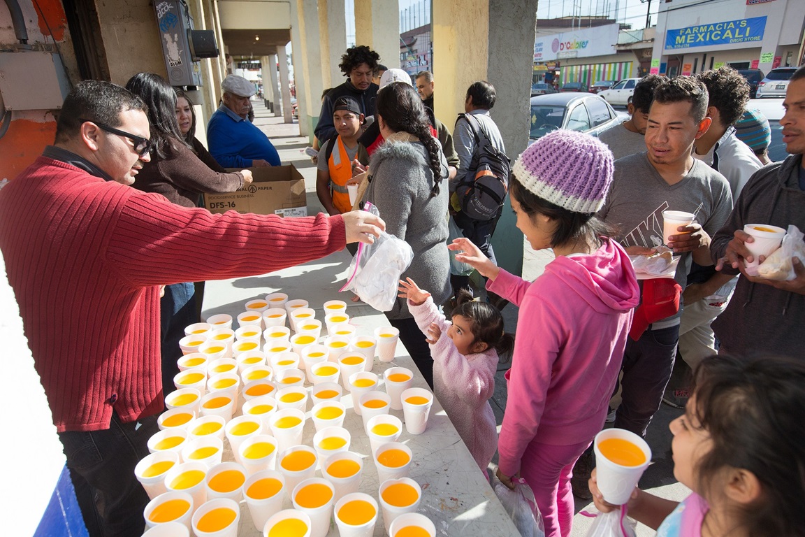 Hector Rodolfo Solorio Castillo (left) of La Gran Comision Methodist Church in Mexicali, Mexico, hands out hygiene kits to migrant families receiving a meal at El Divino Redentor Methodist Church in Mexicali. While UMCOR cannot distribute them to children in the U.S government-run holding facilities, since March the agency has delivered 46,128 hygiene kits to six church-run transitional shelters along the U.S-Mexico border. Photo by Mike DuBose, UMNS. 
