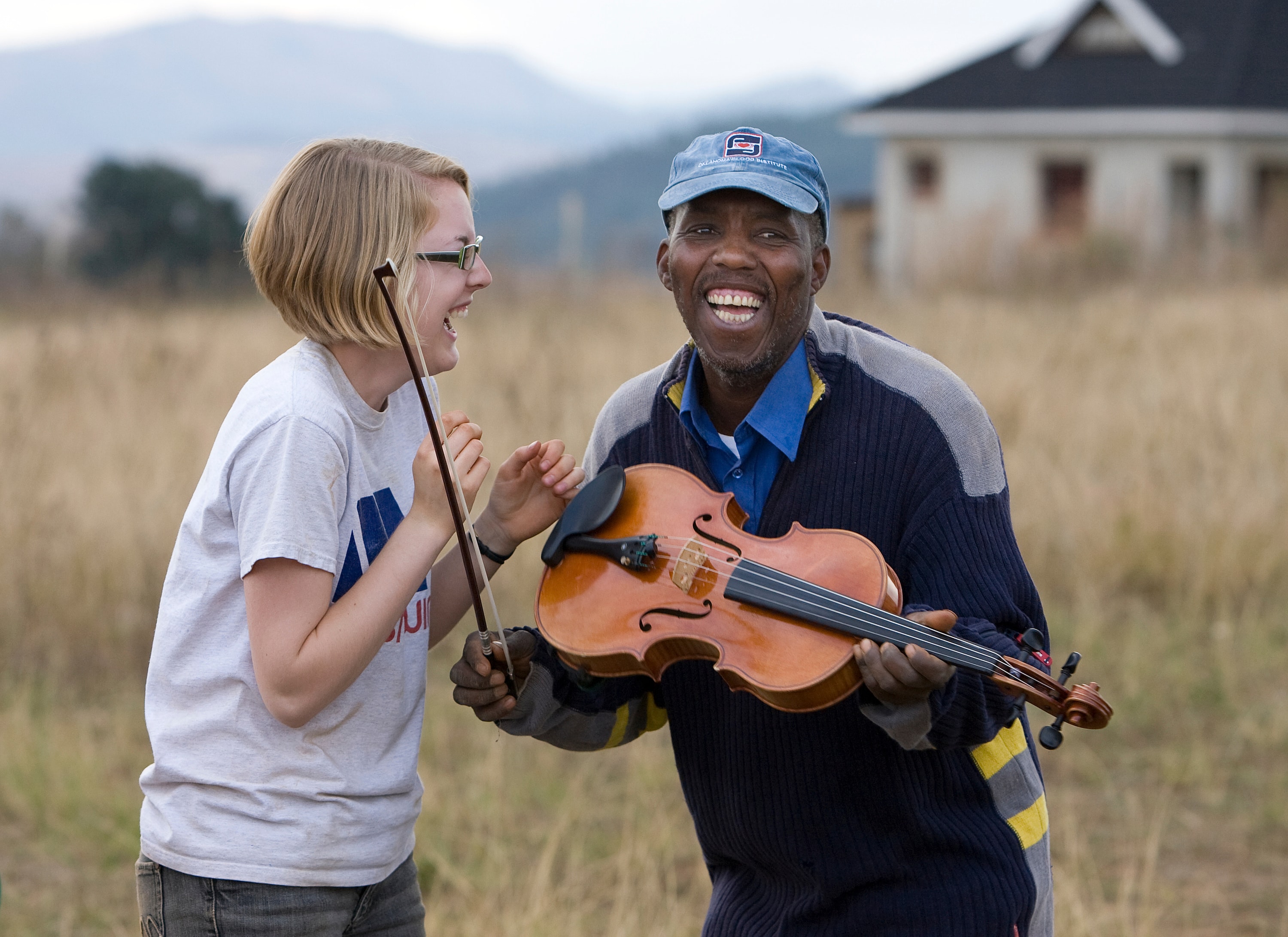 After a week spent teaching volunteers how to lay a concrete foundation in Lomngeletjane, Swaziland, builder John Dlamini receives an impromptu viola lesson from Hannah Plummer of Belmont United Methodist Church in Nashville, Tenn. Photo by Mike DuBose, UM News.