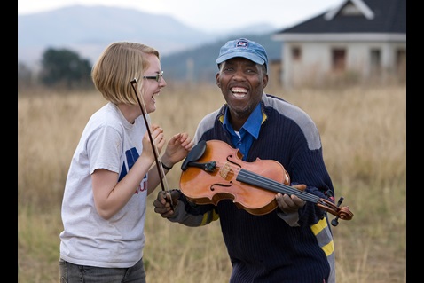 After a week spent teaching volunteers how to lay a concrete foundation in Lomngeletjane, Swaziland, builder John Dlamini receives an impromptu viola lesson from Hannah Plummer of Belmont United Methodist Church in Nashville, Tenn. Photo by Mike DuBose, UM News.