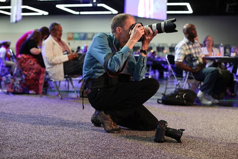 Mike DuBose, photographer with United Methodist News Service, captures moments in the plenary hall during the 2016 United Methodist General Conference in Portland, Ore. Photo by Kathleen Barry, United Methodist Communications.