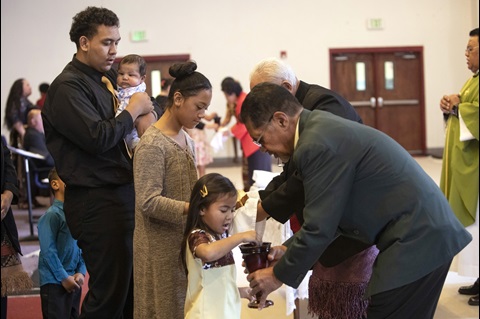 Young adult, Sekope Fainu (left), waits to receive Communion during worship at Tongan United Methodist Church in West Valley City, Utah. Photo by Kathleen Barry, UM News.