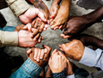 A diverse group of people stand in a circle holding hands. Image by Rawpixel, iStockphoto.com. 