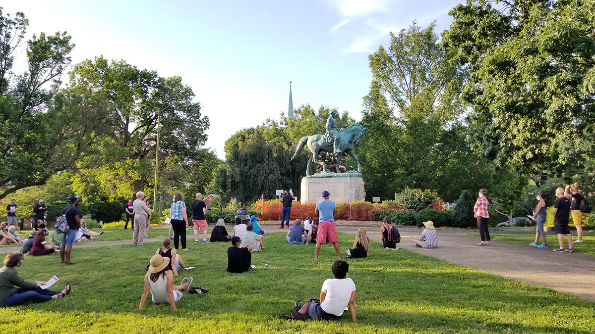 The Rev. Isaac Collins, a United Methodist pastor, co-leads a Bible study, “Swords into Plowshares: What the Bible says about injustice, idolatry, and repentance,” at the base of the Robert E. Lee statue on Market Street Park, Charlottesville, Va., on June 11, 2020. The steeple of First United Methodist Church is visible over the trees in the background. In 2019, Collins and the Rev. Phil Woodson first offered the Bible study using Confederate statues as sites and subject matter. Photo by Phil Woodson.