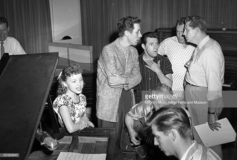 RCA artist Libby Horne recording session at Television, Radio, and Film Commission of the Methodist Church, (TRAFCO), Nashville, 1955 - 1957. RCA then rented this studio and office space from the Methodist Church. L-R: KWTO announcer Joe Slattery, Horne, Chet Atkins, Foggy River Boys member Charlie Hodge (hand on chest), guitarist Homer Haynes, pianist Floyd Cramer in foreground, Foggy River Boys members Earl Taylor and Monty Matthews. Photo by Elmer Williams/Country Music Hall of Fame and Museum/Getty Images.