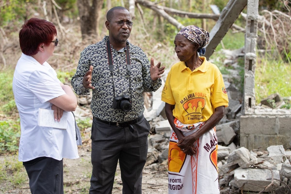 UM News reporters the Rev. João Sambo (center) and Kathy Gilbert (left) visit with a survivor of Cyclone Idai in front of her home in Dondo, Mozambique, which was destroyed by the storm. (Photo by Mike DuBose, UM News)