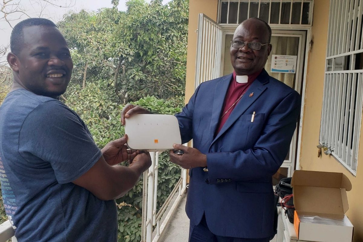 Pierre Omandjela Tangomo (Left), one of the team’s field staff and Communicator of the Congo Central Conference, provides the conference’s episcopal leader Bishop Gabriel Unda (Right) with equipment during the internet install in East Congo. (Photo courtesy of United Methodist Communications)