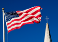 An American flag and church steeple viewed against very clear blue sky. Photo by imdm, iStockphoto.com.