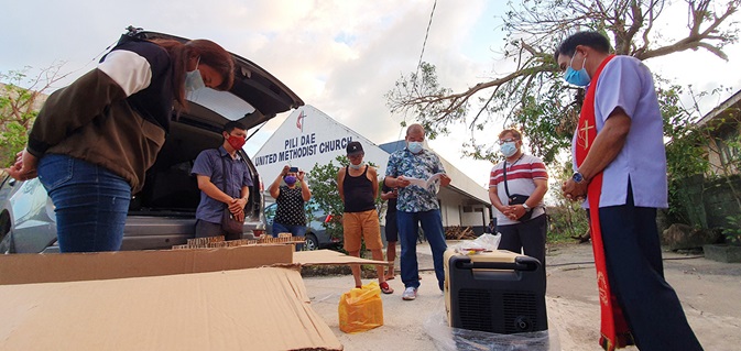Bishop Rodolfo A. Juan (in red stole) and a team of United Methodists pray over generators for the Bicol Philippines Conference. The generators from United Methodist Communications are being loaned to churches to provide free charging to communities affected by a series of powerful typhoons in the Philippines. Photo by Jerome Mercado.