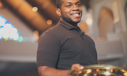 Smiling young adult holding an offering plate. Stock Photo. LeadingIdeas