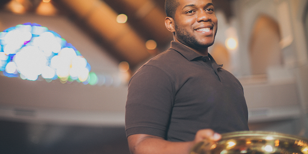 Smiling young adult holding an offering plate. Stock Photo. LeadingIdeas