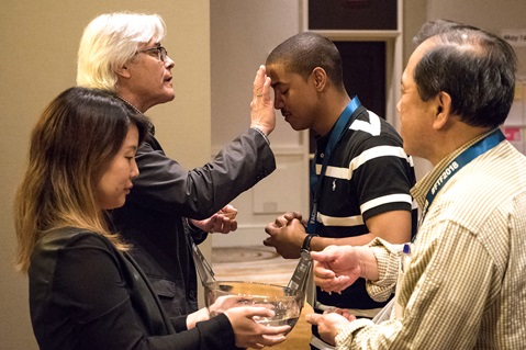 The Rev. Jerome R. DeVine (left, rear) makes the sign of the cross on the Rev. Kyland Dobbins during a reaffirmation of baptism at Facing the Future 2018, an event for clergy in cross-racial/cross-cultural appointments, in Newark, N.J. DeVine described the service as “both a remembering of how we are claimed by God's grace in baptism as well as the ongoing gift of grace that heals and strengthens us in the midst of the storms of life and ministry.” File photo by Joey Butler, UMNS.