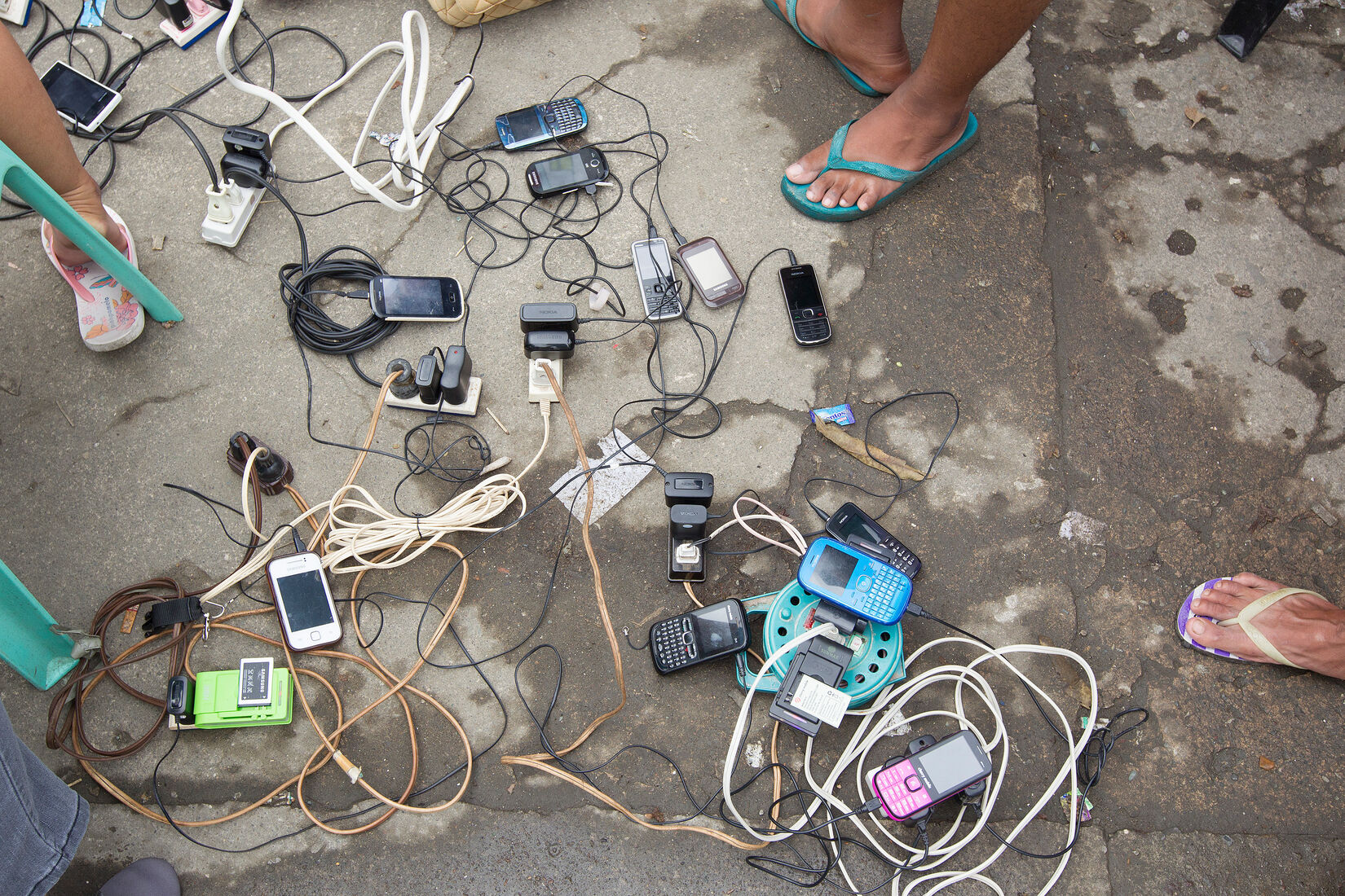 Survivors of Typhoon Haiyan charge their cell phones from a generator at the city hall in Tacloban, Philippines. (A UMNS photo by Mike DuBose.)