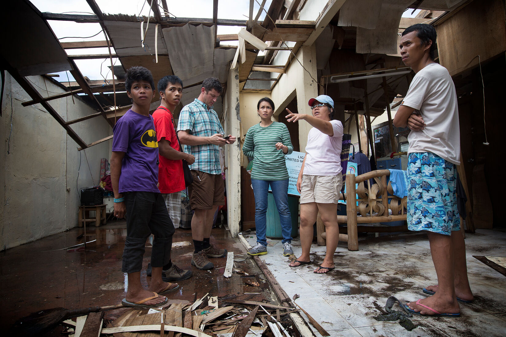 April Mercado (third from right) listens as Pastor Iris Picardal Terana describes the damage from Typhoon Haiyan at Light and Life UMC in Tacloban, Philippines. (Photo by Mike DuBose, UM News.)