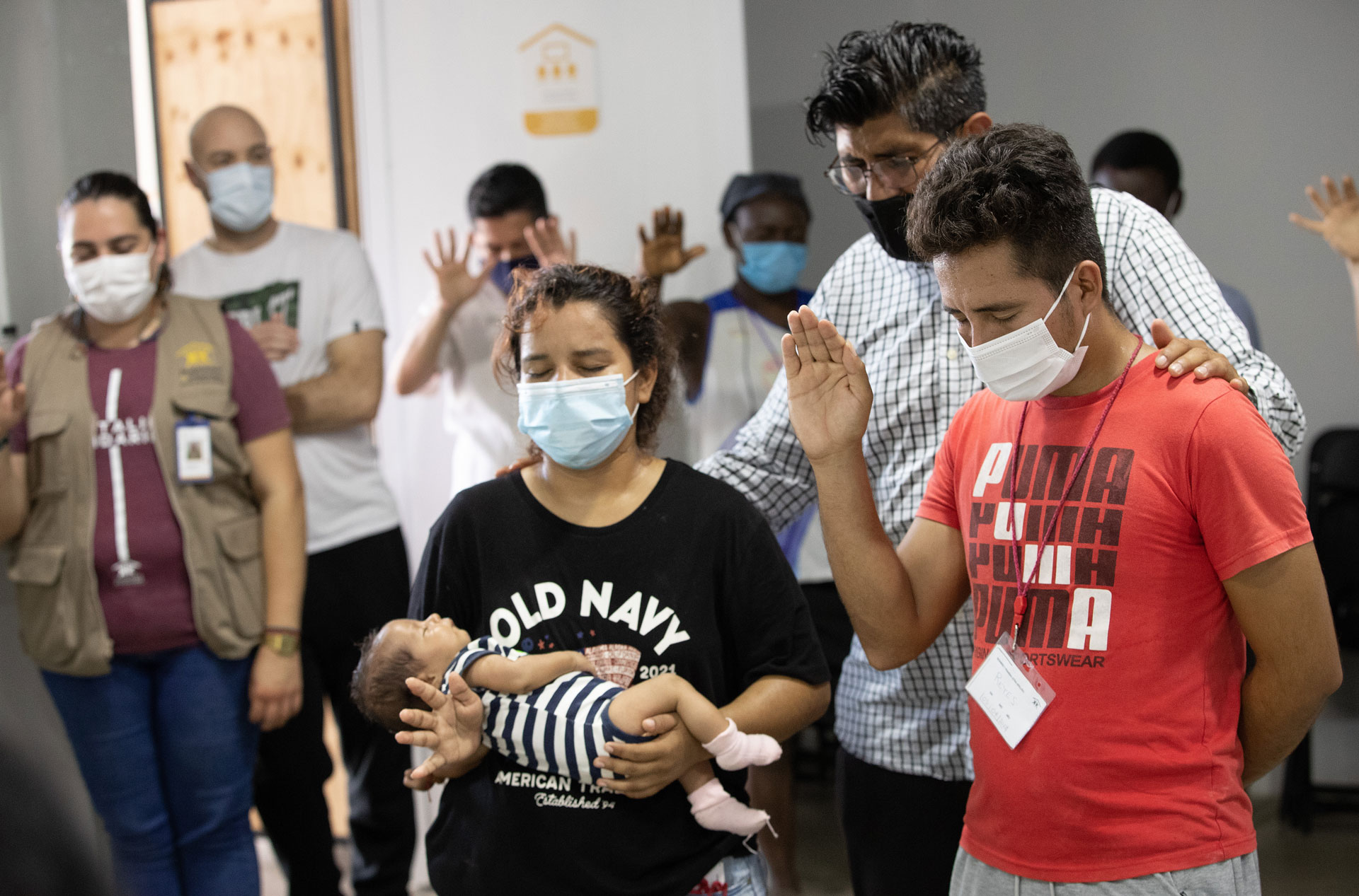 The Rev. Uzi Castañeda Morales of the Methodist Church in Mexico leads a prayer for Nancy, Jose and their 11-day-old daughter, Dina, after the baby was baptized at the Hospitalidad y Solidaridad shelter in Tapachula, Mexico. Photo by Mike DuBose, UM News.
