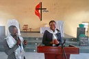 A missionária Tatenda Mujini fala para os membros da Igreja após a visita ao Hospital. Ao lado, está o irmão Salvador Chicosseno traduzindo para Igreja e a missionária. MaNdanji, foto de João Nhanga.