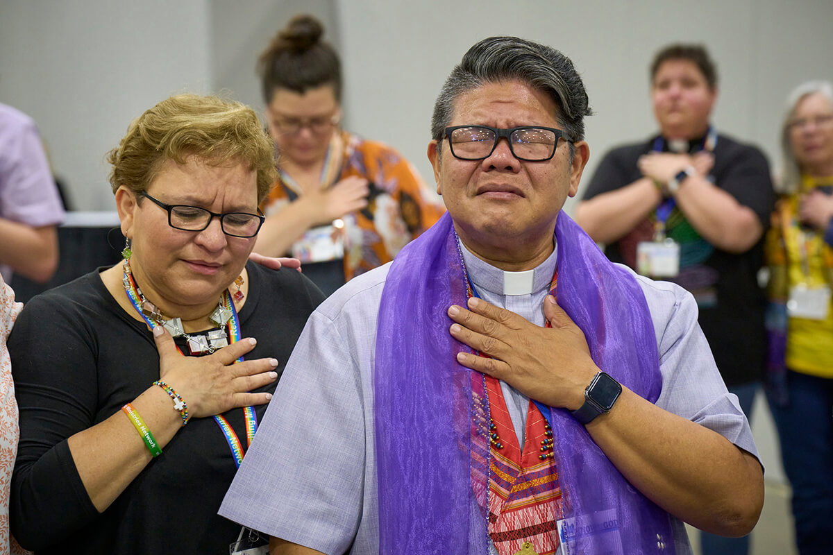 The Rev. Izzy Alvaran (right) and others pray together on May 1 after the 2024 United Methodist General Conference, meeting in Charlotte, N.C., voted to remove the denomination's ban on the ordination of "self-avowed practicing” gay clergy — a prohibition that dated to 1984. Alvaran is on the staff of the Reconciling Ministries Network, which has unveiled a new strategic plan after success at last year’s General Conference. File photo by Paul Jeffrey, UM News.