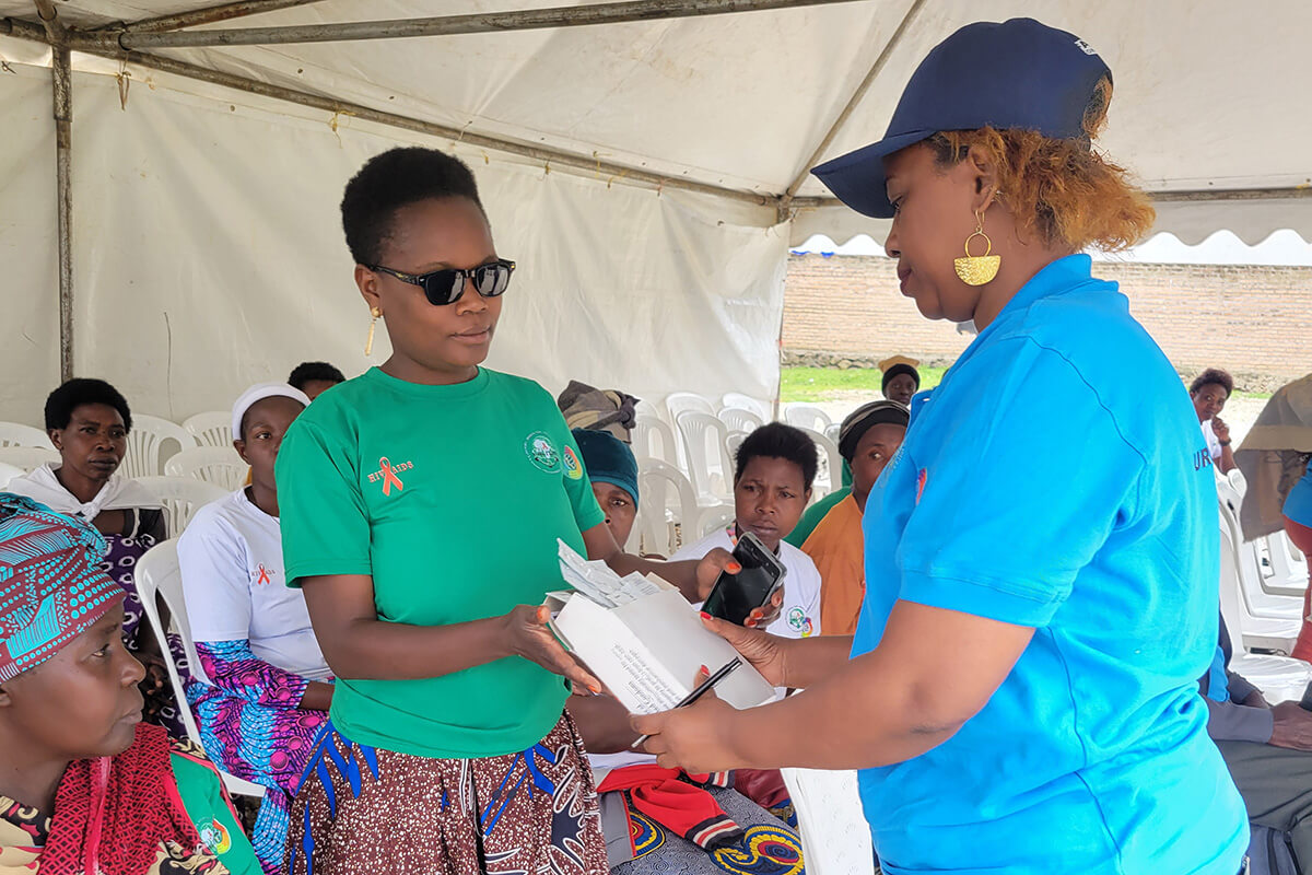Janat Twahirwa from Wiceceka distributes condoms to participants during a World AIDS Day event on Dec. 1 in the Mukamira Sector of Rwanda’s Nyabihu District. “Wiceceka” means “do not keep silent” in English.  During the event, Twahirwa had a particular focus on providing condoms to peer educators, so that they can further share them with their peers as part of ongoing HIV prevention efforts. Photo by Samuel Iraguha Shema.
