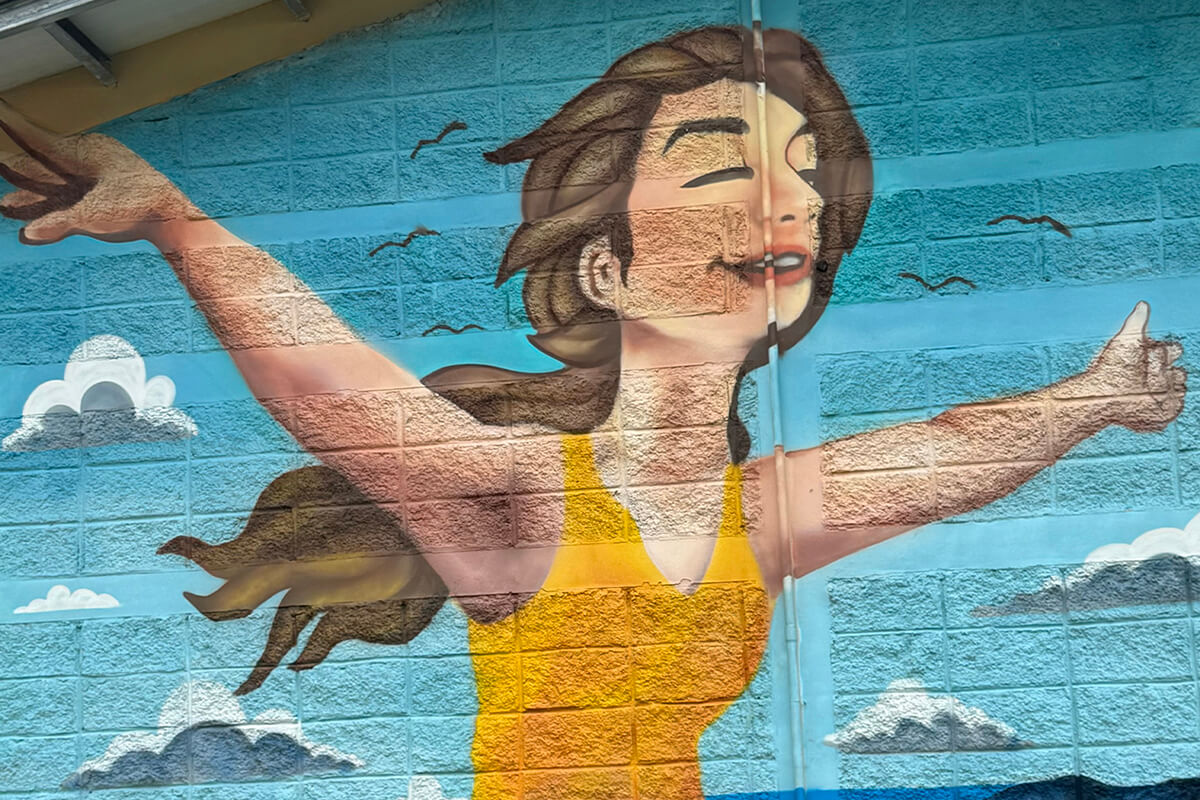 A mural depicting an immigrant woman opening her arms as a symbol of freedom and hope is displayed on the façade of one of the buildings that houses migrants at the government-run Irregular Migrant Assistance Center in Danlí, Honduras. The center includes a clinic supported by the United Methodist Committee on Relief and United Methodist Board of Global Ministries. Photo by the Rev. Gustavo Vásquez, UM News.