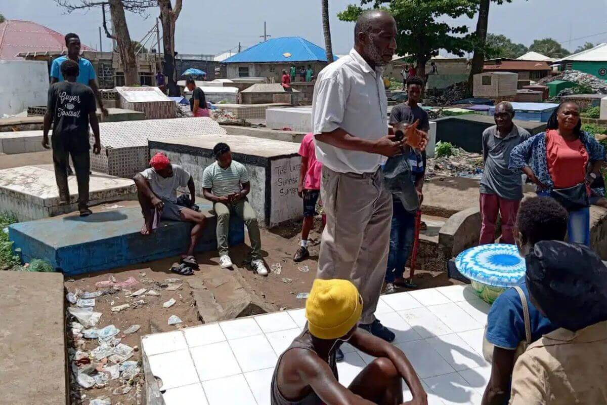 Rev. Caleb S.G. Dormah, Liberia Annual Conference National in Mission, preaches to young adults among the tombs of a Monrovian cemetery, where unhoused people gather. Photo: Liberia UMC At-Risk Youth Center