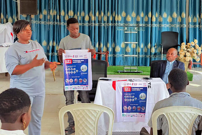 Judith Yanga Osongo (left), director of communications for the East Congo Episcopal Area, raises awareness about Ebola prevention measures at a United Methodist church in Beni, Congo, in the Kivu Annual Conference. This grassroots communications campaign, jointly supported by United Methodist Communications and Global Ministries, includes distribution of posters and essential prevention messages in the areas affected by the Bundibugyo virus outbreak. Photo courtesy of the East Congo Episcopal Area.