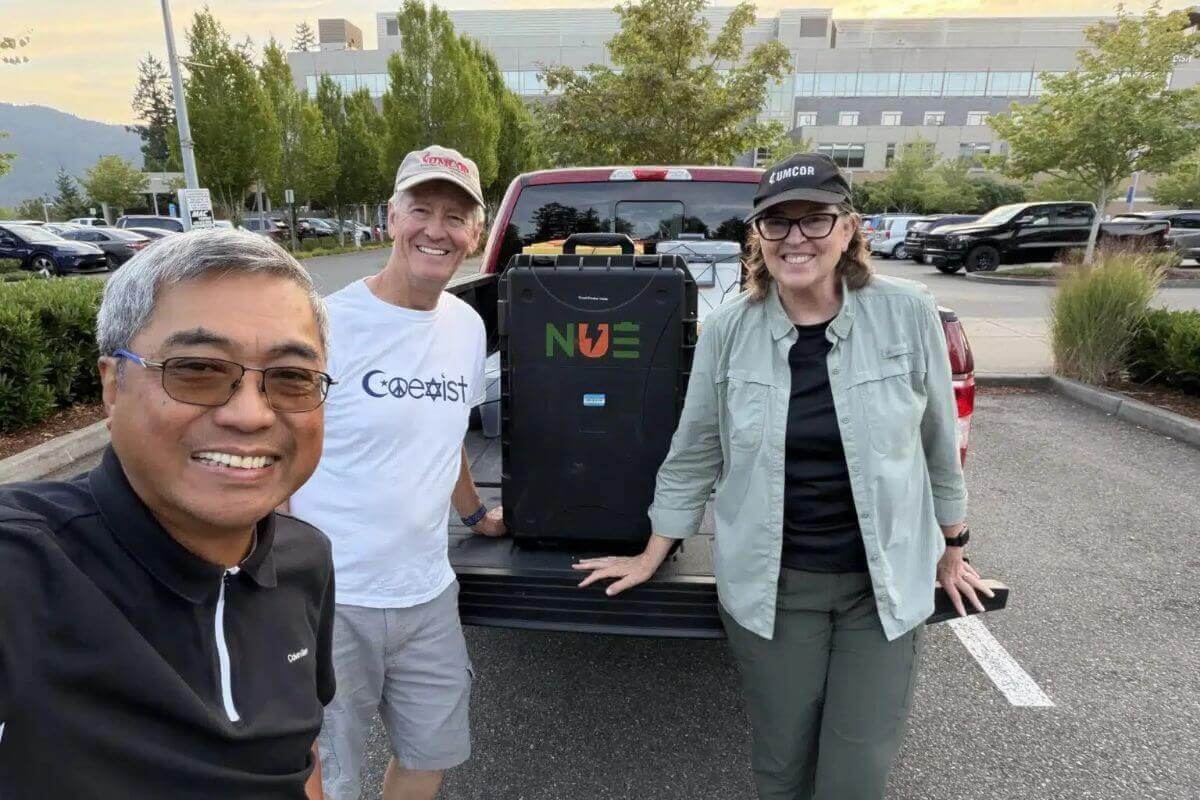 Rev. David Valera (left), executive director of Connectional Ministries for the Pacific Northwest Annual Conference, posing next to a solar suitcase with Dana and Kathy Bryson, co-disaster response coordinators for the PNW Conference. Photo: Beverly Touchton